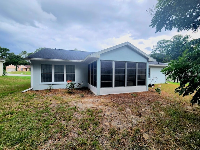 rear view of property featuring a lawn and a sunroom