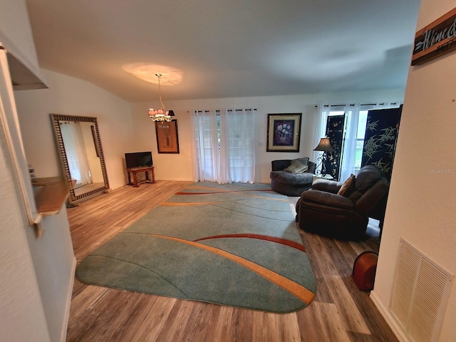 living room with lofted ceiling, wood-type flooring, and an inviting chandelier