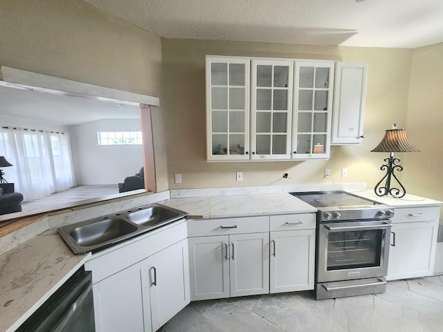 kitchen with a textured ceiling, sink, stainless steel appliances, and white cabinets