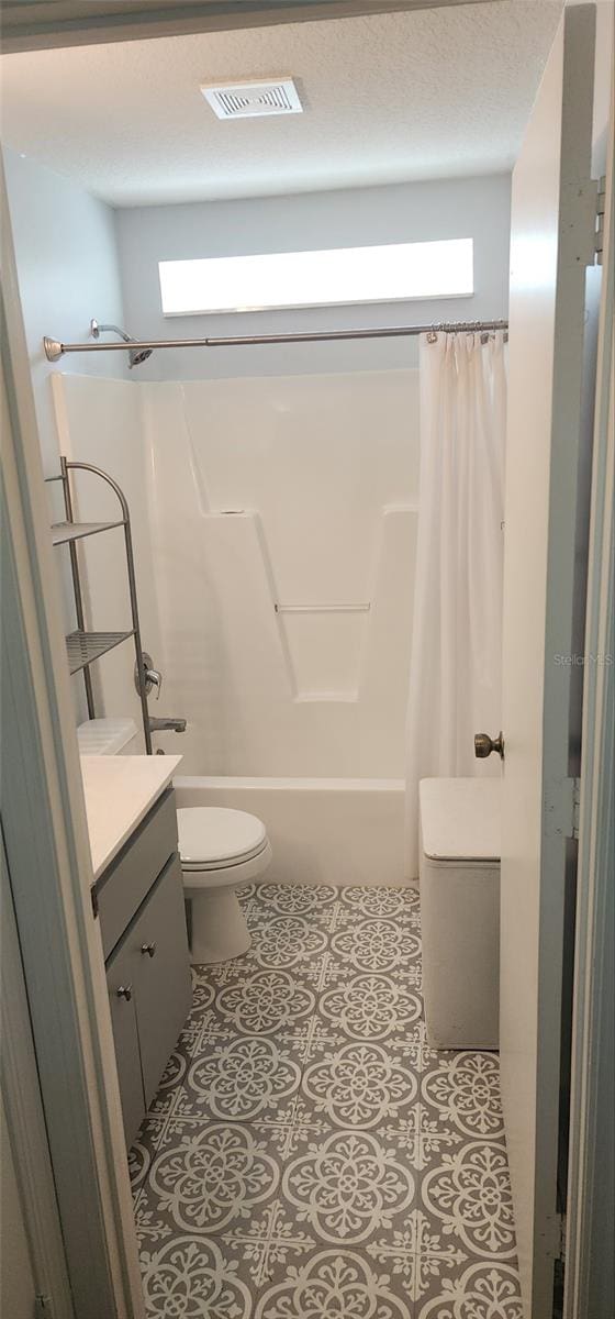 full bathroom with a textured ceiling, vanity, toilet, and shower / bath combination with curtain