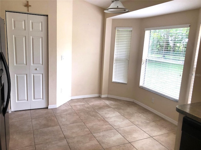 unfurnished bedroom featuring a closet, stainless steel fridge, and light tile patterned flooring