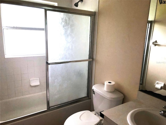 full bathroom with combined bath / shower with glass door, vanity, and toilet