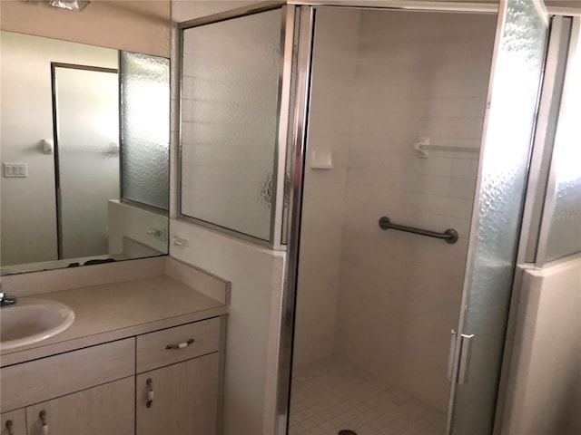 bathroom featuring a shower with door and vanity