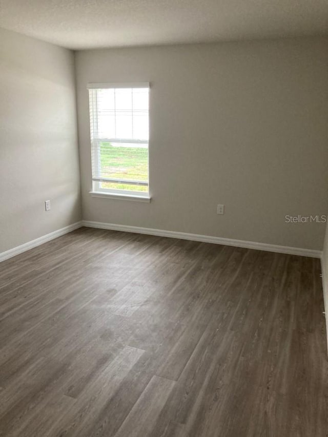 empty room featuring a textured ceiling and dark hardwood / wood-style floors