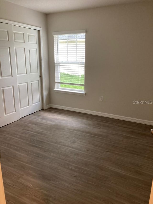 unfurnished bedroom with dark wood-type flooring and a closet