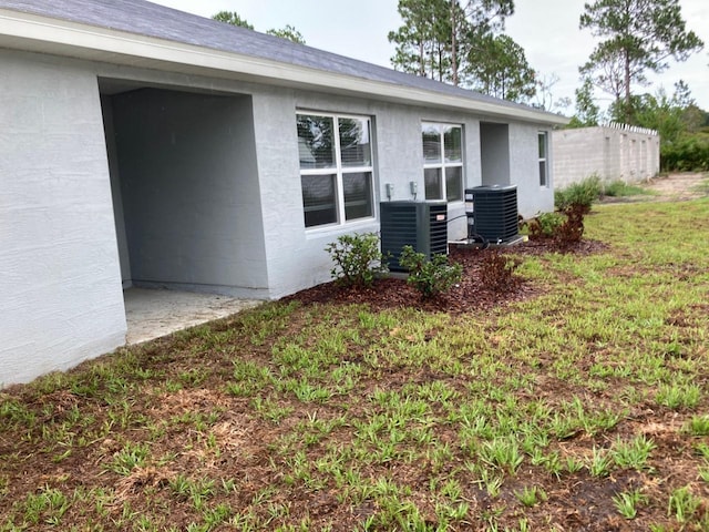 view of property exterior with central AC and a lawn