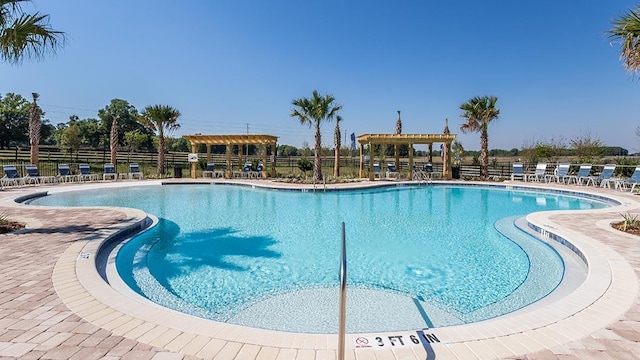 pool with fence, a pergola, and a patio