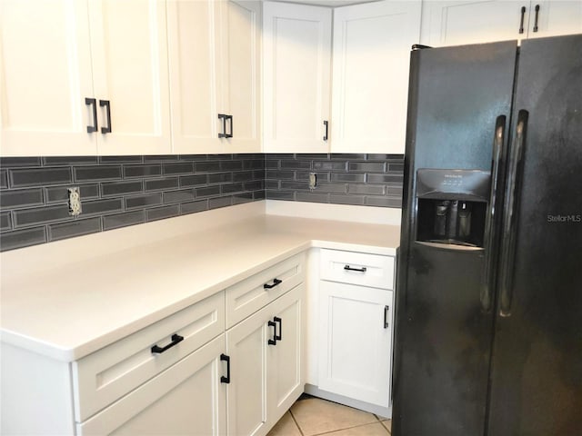 kitchen featuring white cabinets, black refrigerator with ice dispenser, backsplash, and light tile patterned flooring