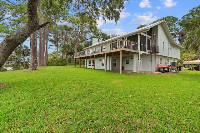 rear view of house with a deck, a lawn, and a chimney