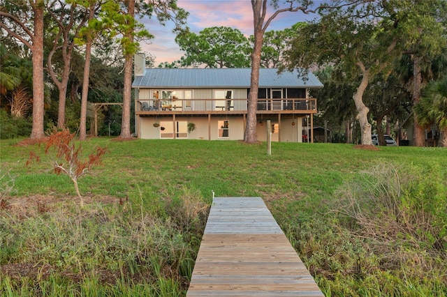 back of house featuring a chimney, a yard, and metal roof