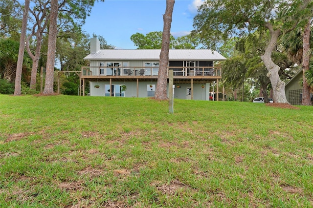 rear view of property with a wooden deck, a yard, and a chimney