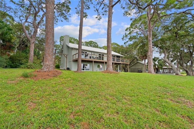 back of property featuring a yard, a deck, and a chimney