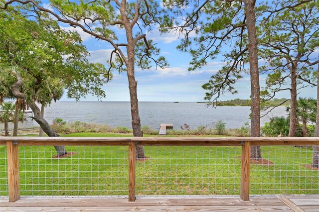 wooden terrace with a yard and a water view