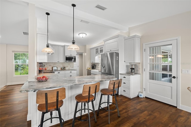 kitchen featuring visible vents, vaulted ceiling with beams, decorative backsplash, appliances with stainless steel finishes, and a peninsula