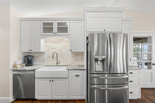 kitchen with a sink, light stone counters, backsplash, appliances with stainless steel finishes, and white cabinets