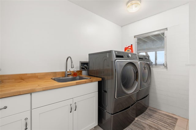 laundry area with cabinet space, light tile patterned flooring, washing machine and dryer, and a sink