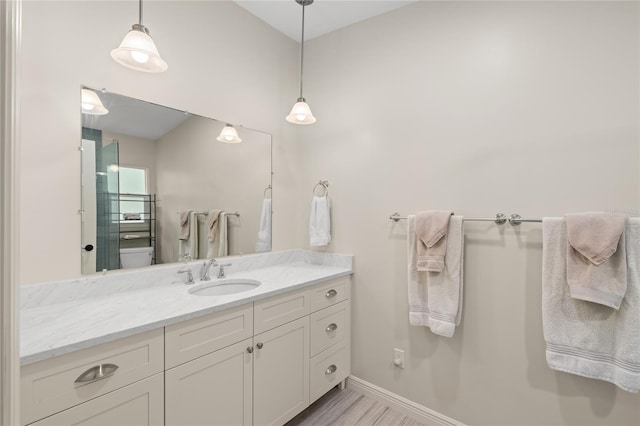 bathroom featuring toilet, vanity, and baseboards