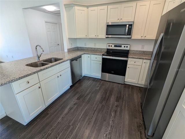 kitchen with dark hardwood / wood-style flooring, kitchen peninsula, sink, appliances with stainless steel finishes, and white cabinets