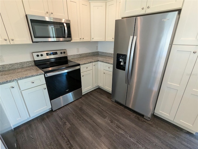 kitchen with white cabinets, appliances with stainless steel finishes, light stone countertops, and dark hardwood / wood-style flooring