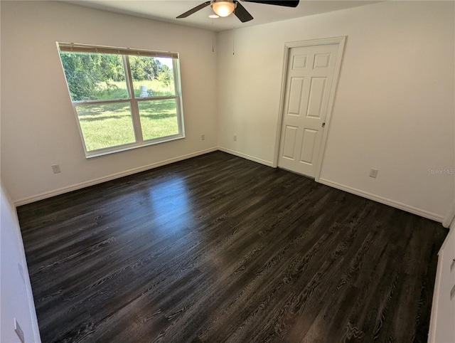 empty room with ceiling fan and dark hardwood / wood-style flooring