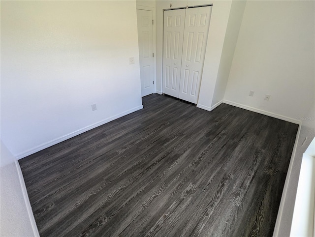 unfurnished bedroom with dark hardwood / wood-style flooring and a closet