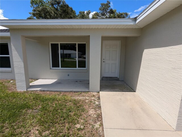 view of exterior entry featuring a patio area and a yard