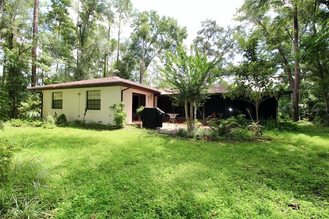 back of property with stucco siding and a yard