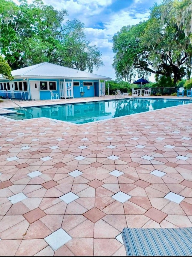 community pool with fence and a patio