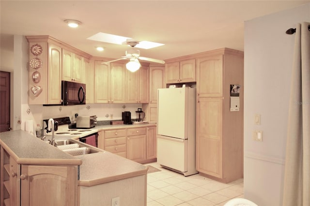 kitchen featuring freestanding refrigerator, a peninsula, light brown cabinetry, black microwave, and a sink