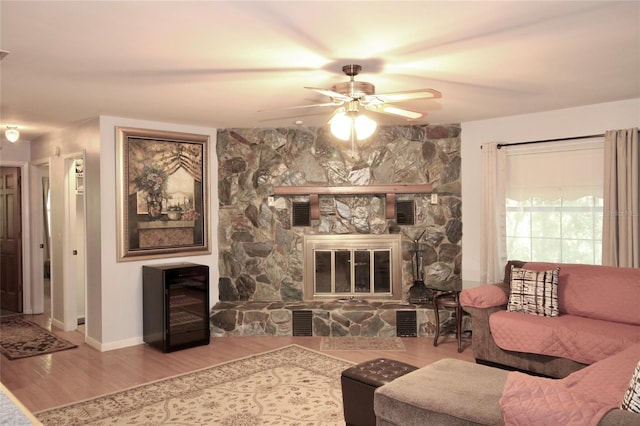 living room featuring ceiling fan, beverage cooler, wood-type flooring, and a fireplace