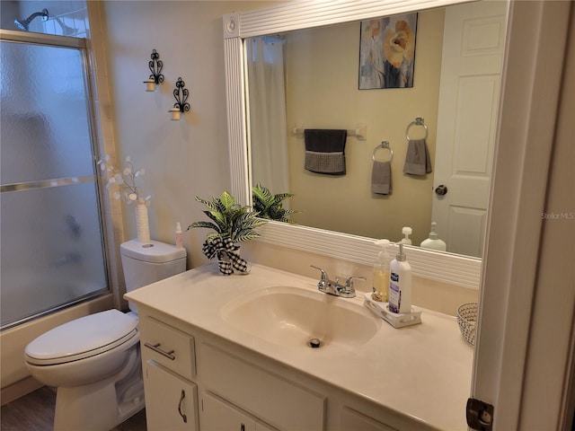 full bathroom featuring hardwood / wood-style flooring, vanity, toilet, and shower / bath combination with glass door