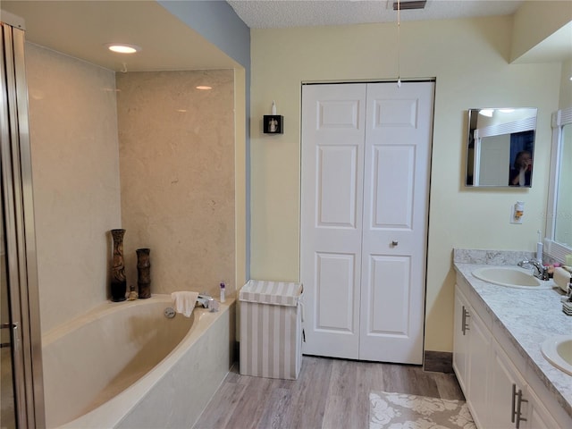 bathroom with a tub to relax in, vanity, a textured ceiling, and hardwood / wood-style flooring