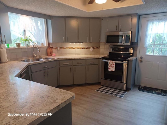 kitchen with appliances with stainless steel finishes, gray cabinetry, a textured ceiling, ceiling fan, and sink