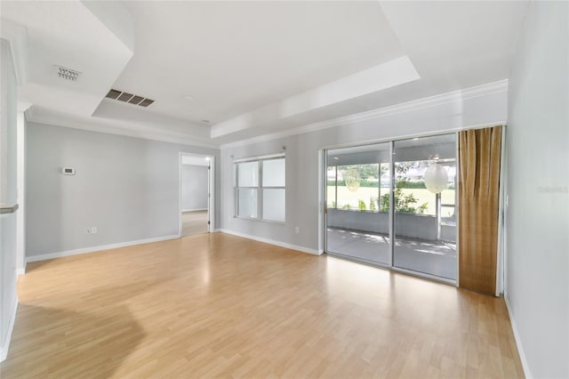 spare room featuring crown molding, a raised ceiling, and light hardwood / wood-style floors