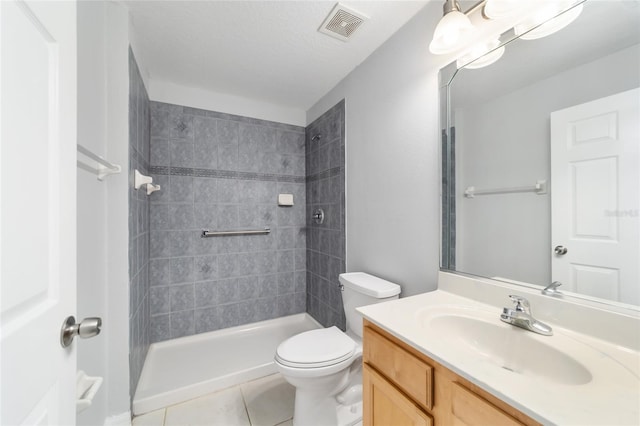 bathroom featuring tile patterned flooring, toilet, vanity, tiled shower, and a textured ceiling