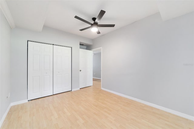 unfurnished bedroom with light wood-type flooring, ceiling fan, and a closet