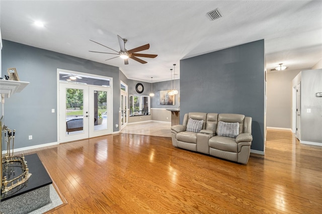 living room featuring ceiling fan, french doors, and light hardwood / wood-style floors