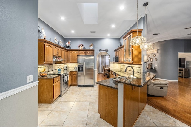 kitchen with dark stone countertops, stainless steel appliances, kitchen peninsula, pendant lighting, and decorative backsplash