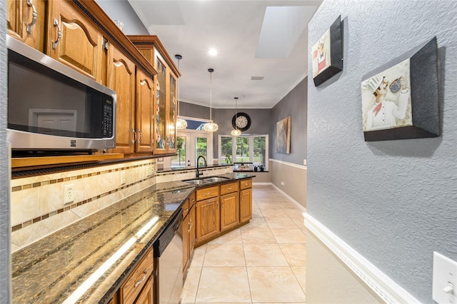 kitchen with decorative light fixtures, appliances with stainless steel finishes, sink, kitchen peninsula, and dark stone counters