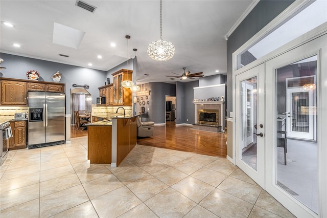 kitchen featuring ceiling fan with notable chandelier, light hardwood / wood-style flooring, backsplash, kitchen peninsula, and appliances with stainless steel finishes