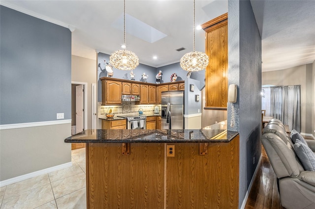 kitchen with a skylight, hanging light fixtures, stainless steel appliances, kitchen peninsula, and decorative backsplash