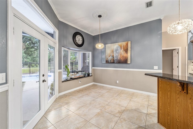 unfurnished dining area featuring tile patterned floors, crown molding, and french doors