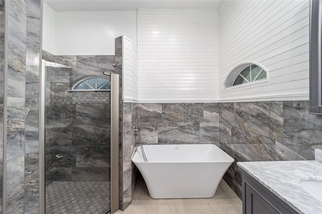 bathroom featuring plus walk in shower, tile walls, and vanity