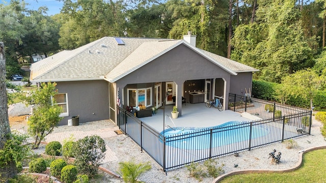 rear view of house featuring a fenced in pool and a patio area