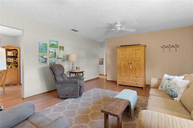 living room with a textured ceiling, hardwood / wood-style floors, and ceiling fan