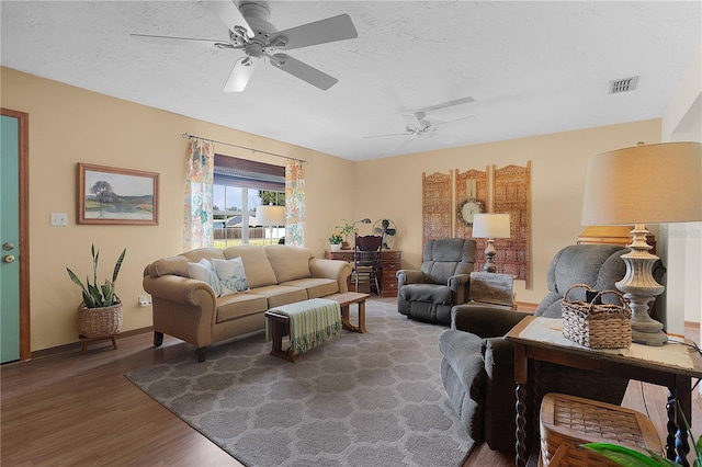 living room with a textured ceiling, wood-type flooring, and ceiling fan