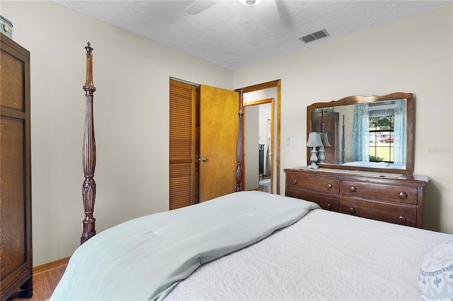 bedroom with a closet, ceiling fan, hardwood / wood-style flooring, and a textured ceiling