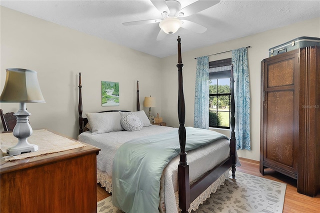 bedroom with ceiling fan, a textured ceiling, and light wood-type flooring