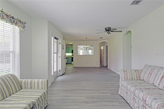 living room featuring a healthy amount of sunlight, ceiling fan with notable chandelier, and light wood-type flooring