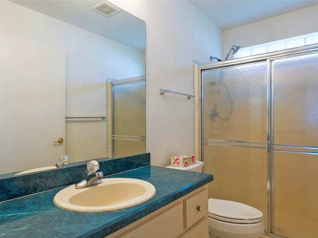 bathroom featuring vanity, a shower with shower door, and toilet